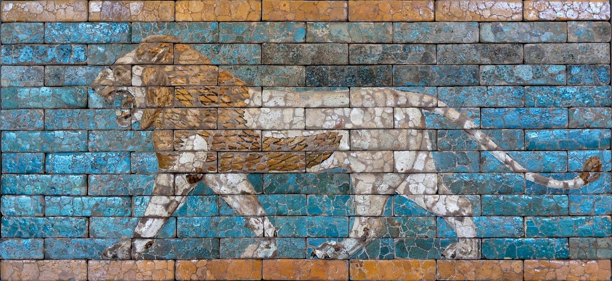 A striding, roaring lion in molded glazed brick — tawny mane, cream body, tail curling up behind — walking left to right across a turquoise-blue field bordered above and below by bands of ochre brick, from the Processional Way of Babylon.