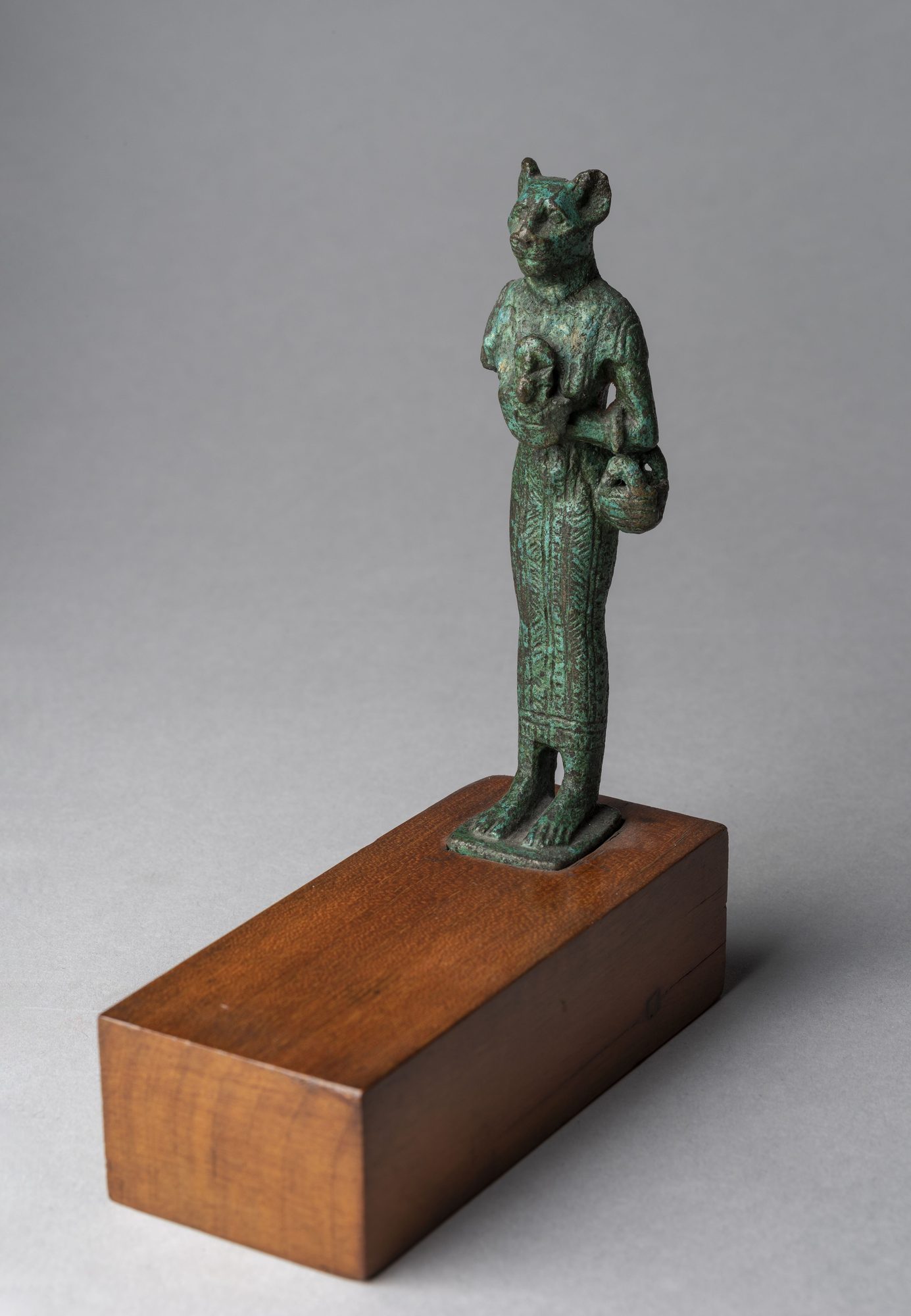 An ancient Egyptian bronze statuette of the goddess Bastet in cat-headed form, a lithe female figure with a lioness-domestic cat head and a broad collar.