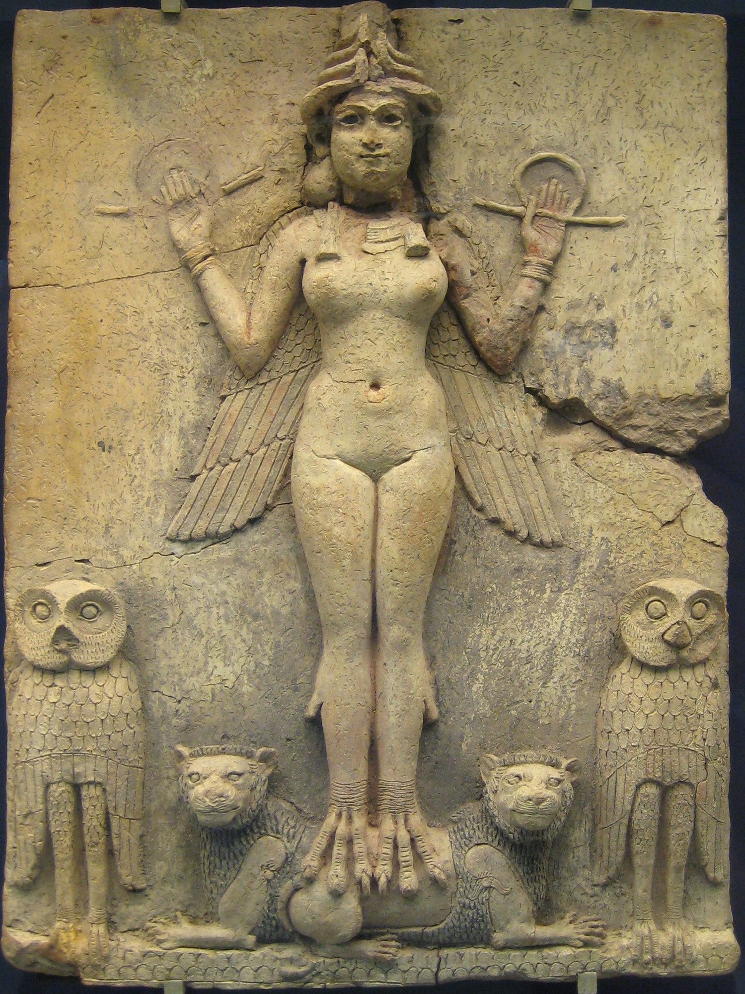The Old Babylonian "Queen of the Night" terracotta relief: a winged nude goddess in a horned headdress, holding a rod-and-ring symbol in each raised hand, standing on the backs of two lions and flanked by two owls, with a scale-pattern mountain base below. The figure has been variously identified as Ishtar, Lilith, or Ereshkigal.