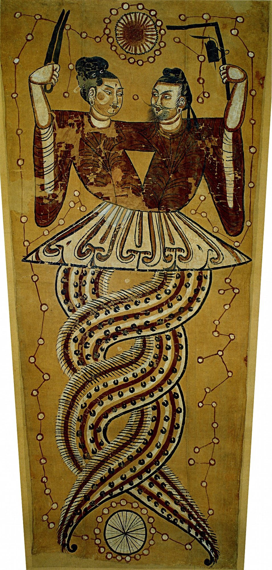 Tang-dynasty silk painting of Fuxi and Nüwa as a human-headed, serpent-bodied pair, their scaled tails entwined in a double helix below a shared white skirt. Nüwa at left raises a compass in her hand; the bearded Fuxi at right raises a carpenter's set-square with an ink-cord; a radiate sun-disc floats above their heads and a spoked moon-disc below the tails, the tan silk ground strewn with linked white dots for the constellations.