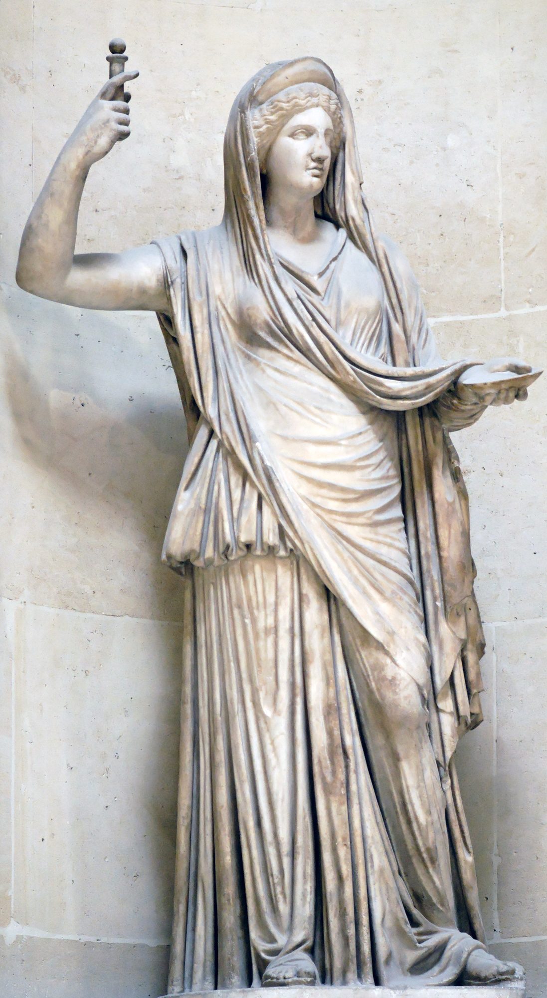 Marble statue of Hera as queen, standing veiled in a long chiton and himation with a diadem band across her brow, her raised right hand holding a sceptre and her extended left hand bearing a shallow offering dish.