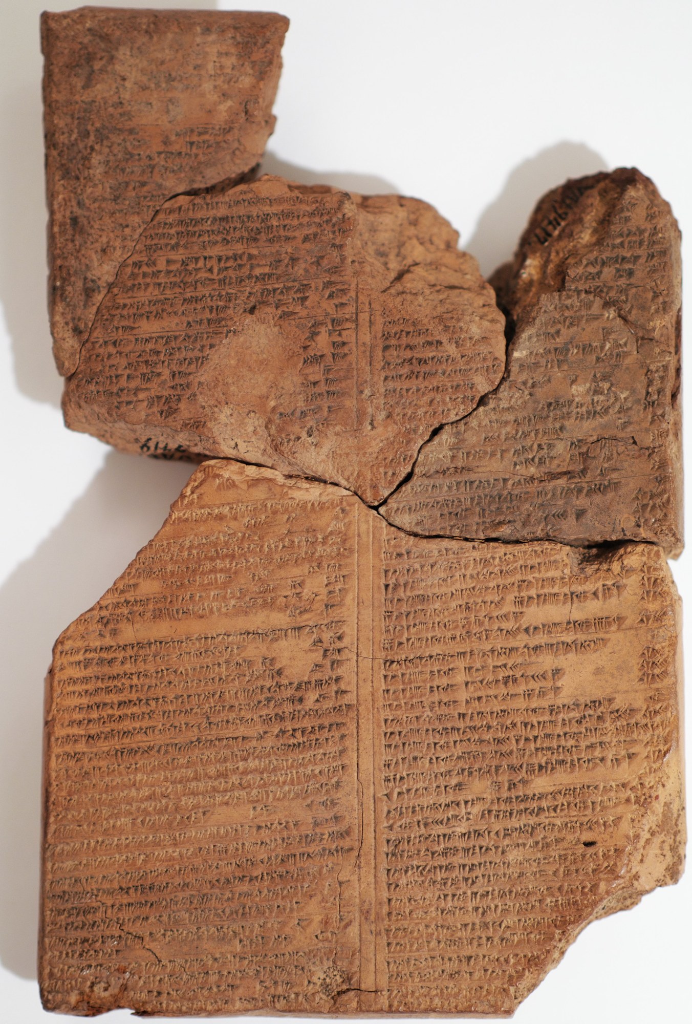 A large fragmentary Babylonian cuneiform tablet, joined from several broken pieces, its surface ruled into columns of dense cuneiform — a copy of the astronomical compendium MUL.APIN, the standard Babylonian handbook of the stars, the paths of the sky and the calendar.