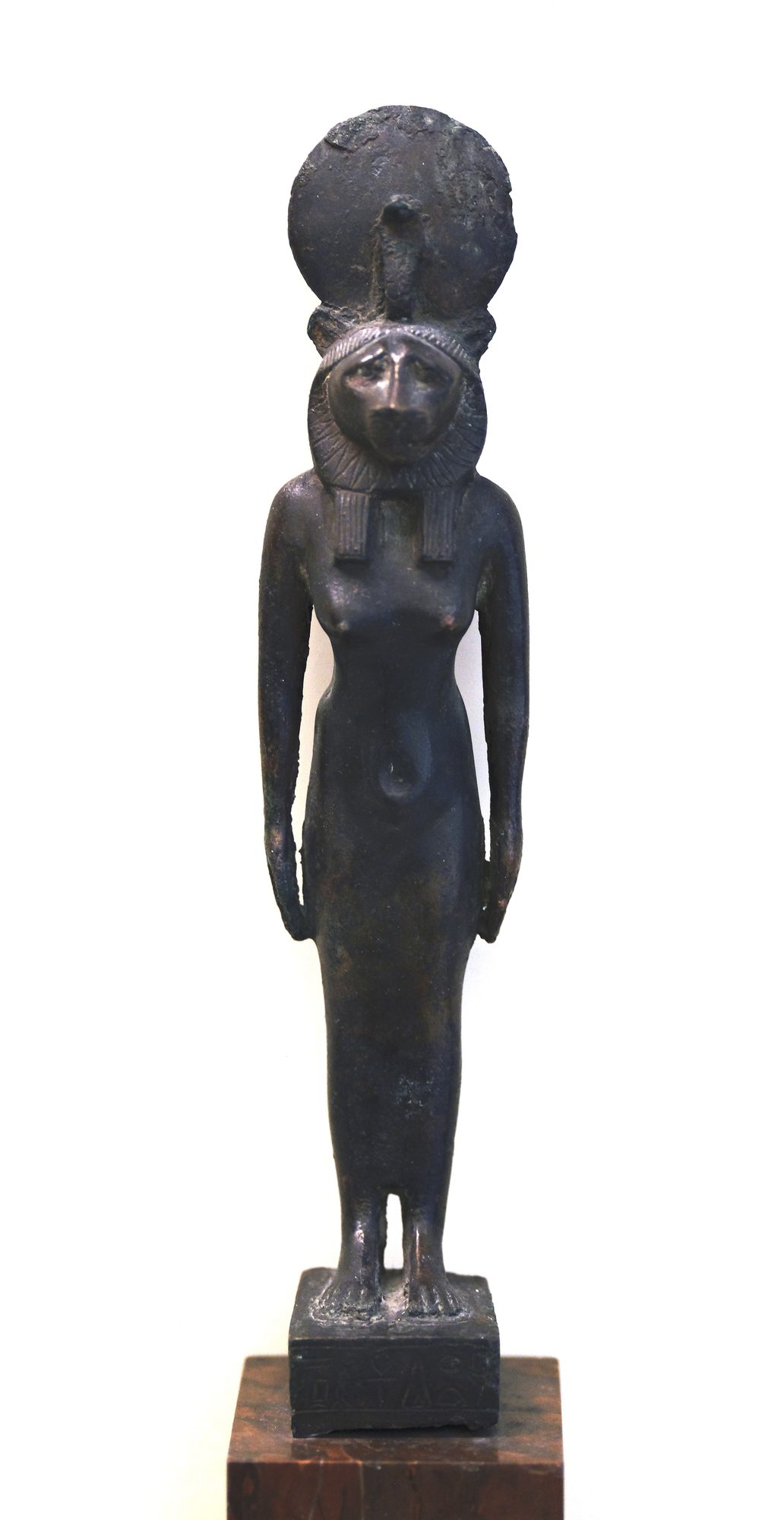 An ancient Egyptian granodiorite statue of the lioness-headed goddess Sekhmet, a slender figure with a sun disk and uraeus at her brow, holding a papyrus sceptre.