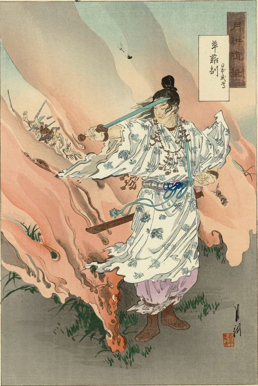 Japanese colour woodblock print of the hero Yamato-Takeru standing amid burning grass, a young man in a white robe patterned with pine-sprigs and hung with strings of curved jewels, drawing the blue-green Herb-Quelling sword Kusanagi across his body to cut back the flames sweeping up around him from the moor.